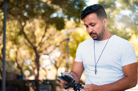 young, handsome, Hispanic Latin boy with beard and short hair, dressed in a white flannel, holding a...