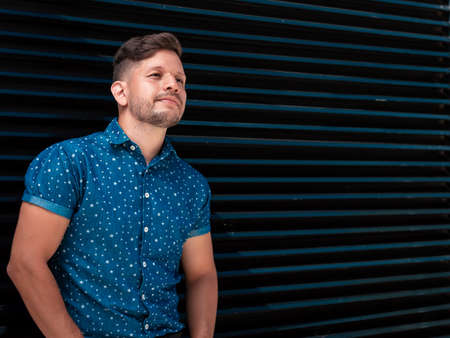 young, handsome, Hispanic Latino boy with a beard and short hair, dressed in a short-sleeved blue...