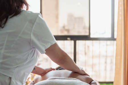 close up of the face of a Hispanic Latin brunette young girl lying face up on a therapy table, smiling as she is being cleaned with a facial cleansing brush.の写真素材