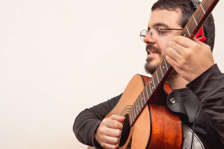 closeup profile shot of a smiling white latin male adult guitar teacher with red headphones, beard,...