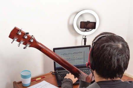 closeup profile shot of a smiling white latin male adult guitar teacher with red headphones, beard,...