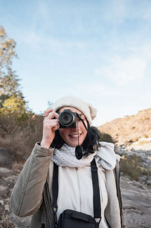 pretty young hispanic latin white girl in pink with hat and black pants posing standing smiling with her eyes closed and hands on her hips smiling with her face up, in a mountainous arid valleyの写真素材