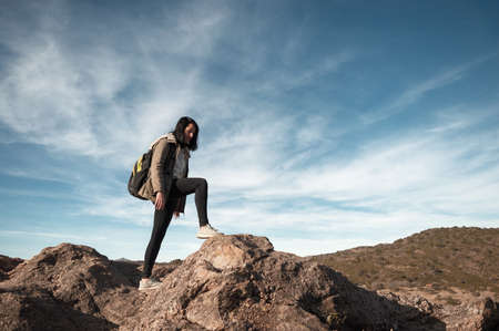 pretty young hispanic latin white girl in pink with hat and black pants posing standing smiling with her eyes closed and hands on her hips smiling with her face up, in a mountainous arid valleyの写真素材