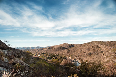 pretty young hispanic latin white girl in pink with hat and black pants posing standing smiling with her eyes closed and hands on her hips smiling with her face up, in a mountainous arid valleyの写真素材