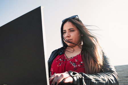 pretty young white hispanic latin business girl with her computer and sunglasses dressed in black...