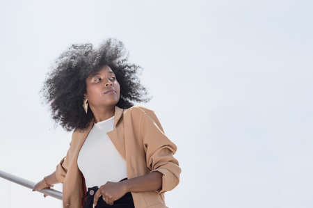 pretty young black Hispanic Latina college girl with afro, glasses and yellow jacket, talking on the...