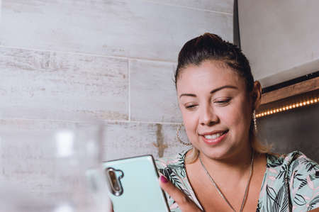 horizontal image of young hispanic latina woman sitting in a coffee shop concentrating on checking...