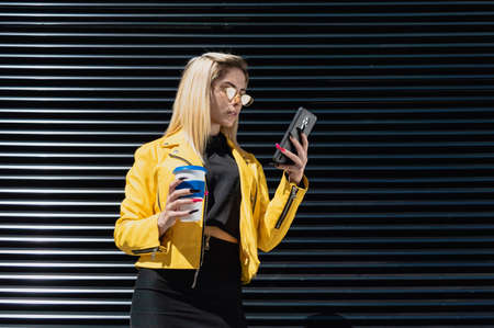 beautiful young blonde hispanic latin girl, with jacket and yellow glasses, stopped on the street...