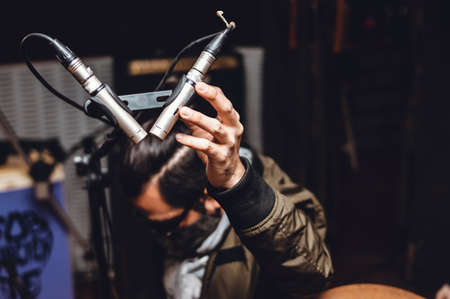 hands of a white person holding a pair of professional condenser microphones on a tripod on a recording set in a professional studio, blurred background, image with copy space.の写真素材