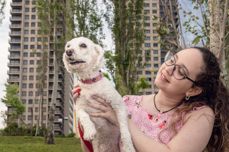 pretty young caucasian girl with curls and glasses sitting in a beautiful urban park outside her...