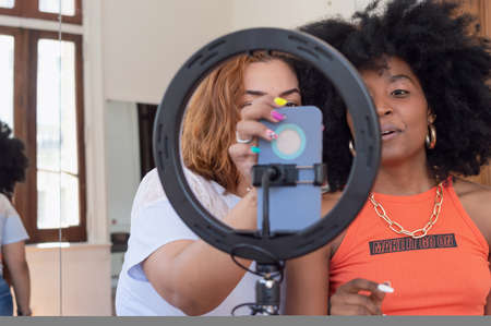 two beautiful young hispanic latin girls friends of different ethnicities, indoors making a video...
