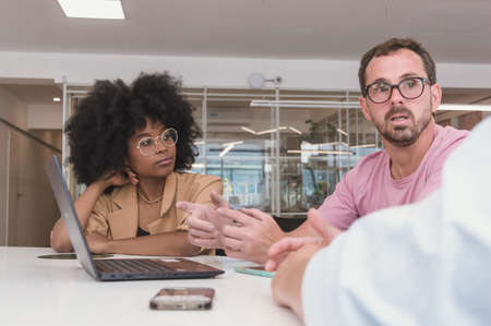 Young Hispanic Latino Afro girl watching a Caucasian Latino adult man with a beard and glasses who...