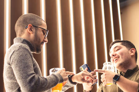 two young latin guys, enjoying themselves, talking to each other and smiling, looking at the time...