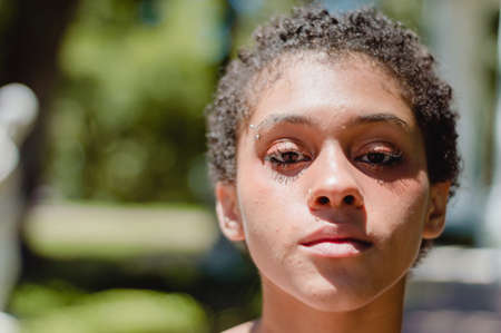 close-up portrait of young Hispanic Latin brunette girl with short hair looking at the camera, standing in a square with a blurred backgroundの写真素材