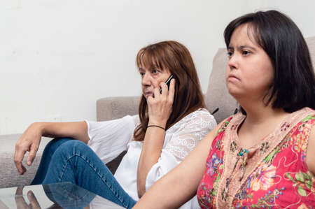 caucasian hispanic latin argentinian mother sitting on the living room floor talking on the phone...
