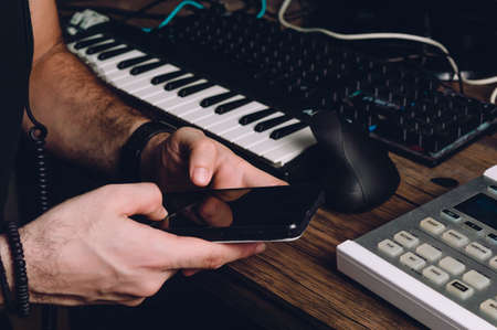 caucasian male hands using a phone in a home studio, sending messages, technology and communication concept.の写真素材