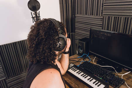 side view of unrecognizable caucasian man in his home recording studio, watching computer analyzing and music, working on music production and composition.の写真素材