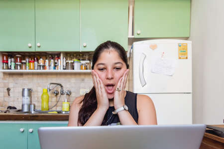 young caucasian venezuelan student woman at home watching the exam note on the computer surprised...