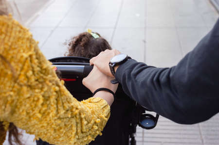 rear view of caucasian couple on street holding hands strolling with baby stroller, copy spaceの写真素材