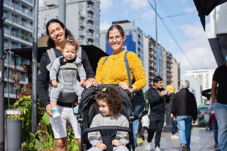 portrait beautiful young caucasian family on the street looking at the camera with funny faces, man and woman with their daughters walking in the city, copy space.の写真素材
