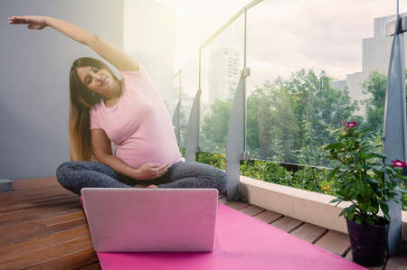 online yoga classes to pregnant women for a healthier life, woman on a pink mat practicing yoga with...
