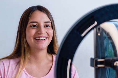 caucasian young woman, social media content creator, is smiling and making a video with her phone and a ring of light, technology concept with copy space.の写真素材