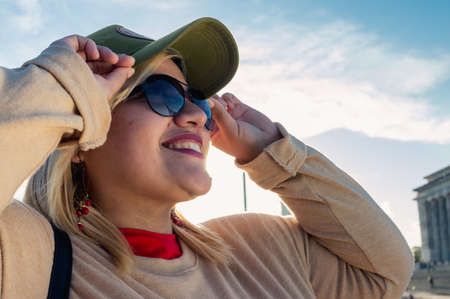 close up portrait caucasian argentinian young latin tourist woman, wearing sunglasses outdoors in the city of buenos aires, smiling looking to the side, with copy space.の写真素材