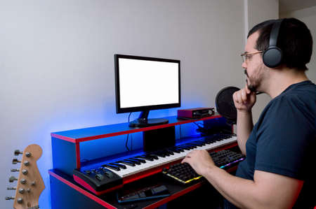 caucasian latin man with headphones and glasses, working sitting in his home music studio thinking...