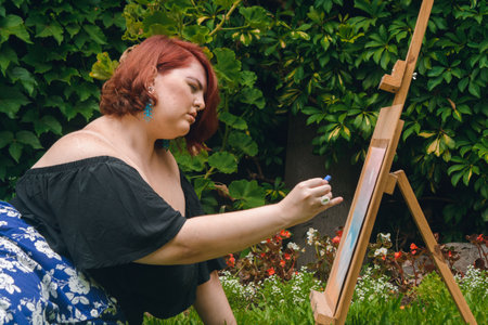 young redhead caucasian latina woman, plus size model, sitting on the grass in her garden with a...