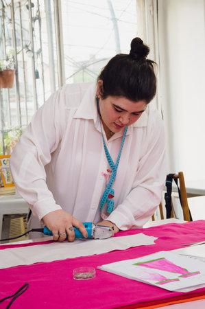 vertical image of caucasian female fashion clothing designer professionals in her workshop working,...
