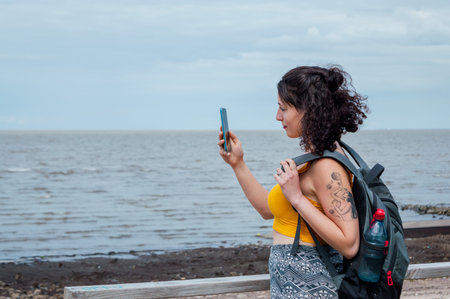 young latin woman traveler, white skin, standing in front of the rio de la Plata in Buenos Aires,...