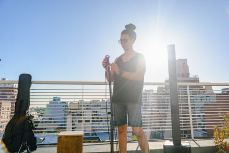 young man sound technician assembling microphone stand, for a live set, on the terrace of a building. copy space.の写真素材