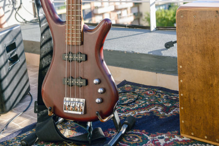 closeup of body of red burgundy bass guitar perched on stand, live music set, music concept, copy...