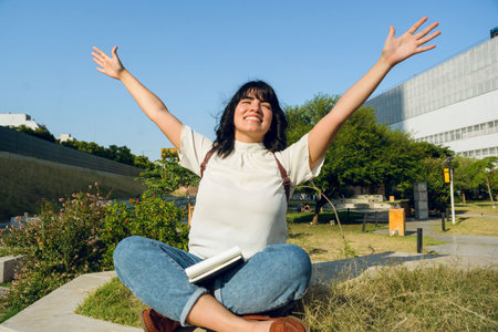 happiness and appreciation towards life, young latin student woman, short hair, happy sitting with open arms and closed eyes, lifestyle conceptの写真素材