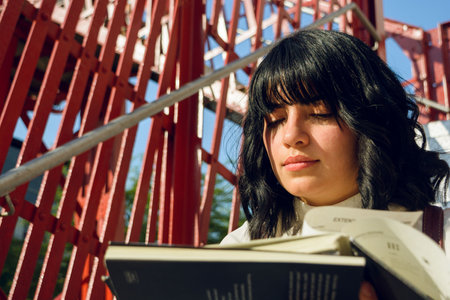 closeup of young latin woman, short hair and white casual clothes, sitting calmly reading a book, students concept, copy space.の写真素材