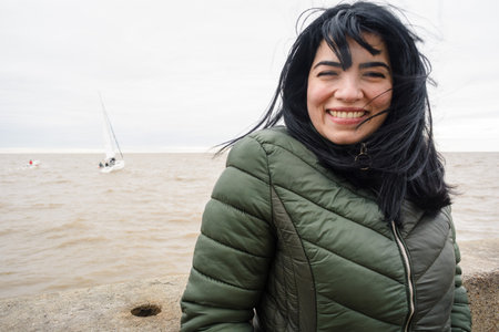 closeup portrait of young venezuelan latina tourist, standing on the pier at the port of olivos in...