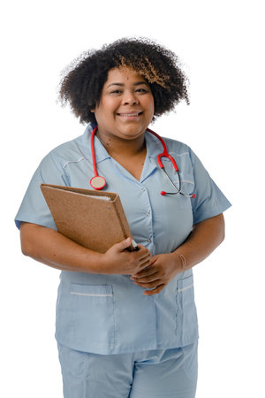 vertical portrait of young afro latina medical woman with stethoscope, blue uniform and holding a folder smiling looking at the camera, white background.の写真素材