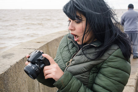 young venezuelan tourist latina woman with her mouth open, she is surprised seeing the photo she...