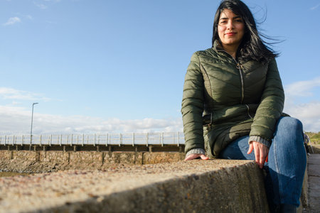 young latin woman tourist enjoying watching the sunrise sitting on the pier in the port of olivos in Buenos Aires, tourism concept, copy space.の写真素材