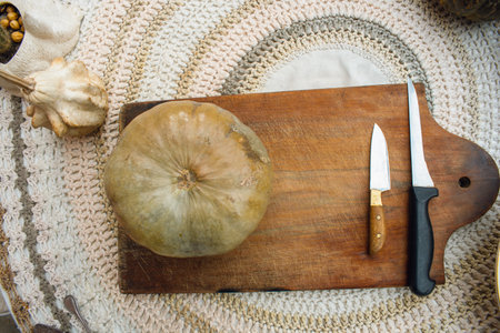 halloween background, a pumpkin and two knives on a wooden cutting board, on a table with copy space