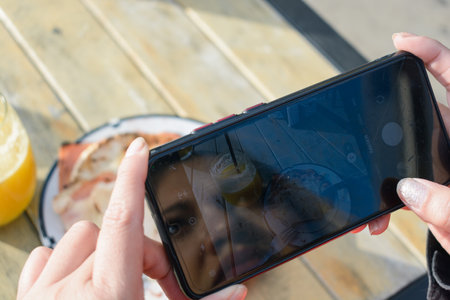 unrecognizable caucasian female hands outdoors, outside restaurant is taking picture of plate of food on table, food and technology concept, copy space.の写真素材