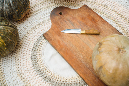 top view of pumpkin and knife on wooden board on table, preparation of recipes with pumpkin, cooking...