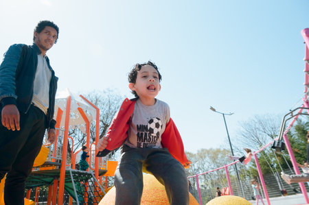 young Venezuelan boy with his father at noon in park jumping playing and having fun, copy spaceの写真素材