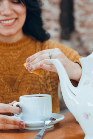 Unrecognizable caucasian woman sitting in restaurant, putting lemon in tea, squeezing half lemon...