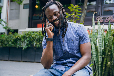 Strong and handsome young african man, with dreadlocks, beard and shirt, happy smiling sitting...