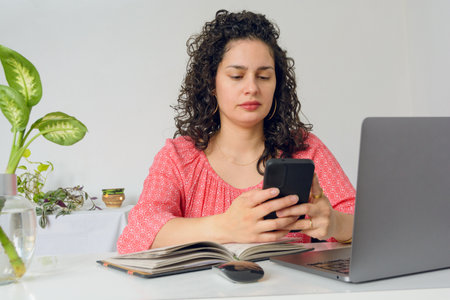 young Latin Venezuelan woman with curlers, home worker sitting in office with her laptop...