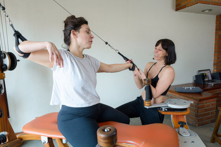 Caucasian female trainer standing assisting her student during training using exercise and...