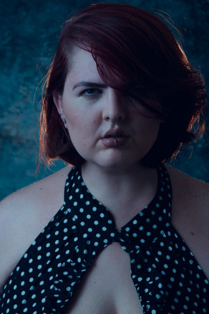 Vertical portrait of young plus size Latina with short hair, light eyes and white skin, looking at camera seriously, close-up, image for social networks.の写真素材