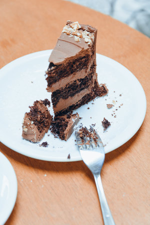 vertical image of slice of chocolate cake cut on plate with fork, on wooden table, copy spaceの写真素材