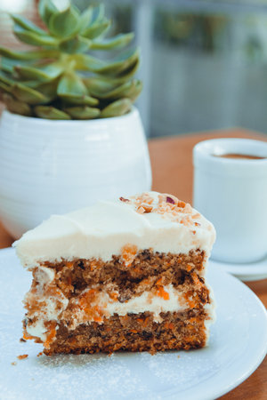 vertical image of slice of carrot cake served on white plate on table in cafe, pastry concept, copy spaceの写真素材